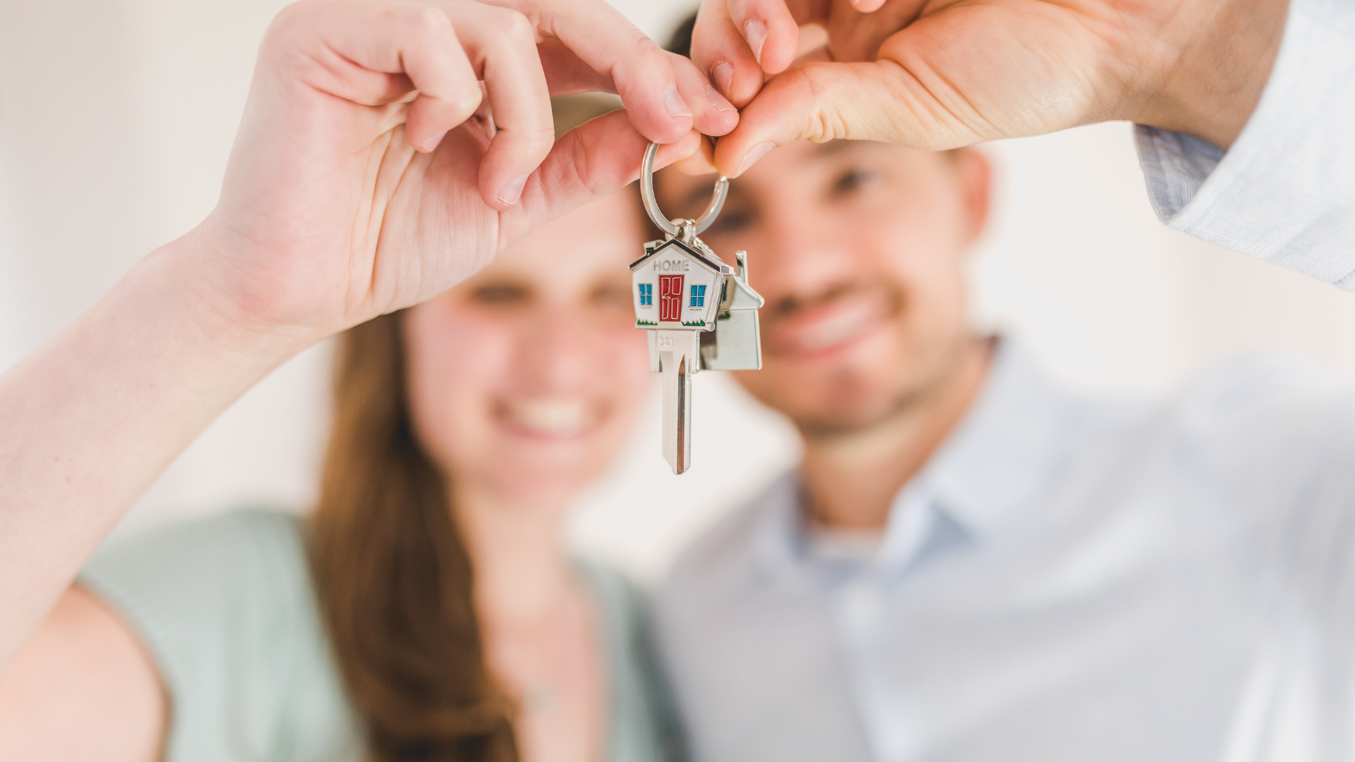 Happy first-time homeowners hold up the keys to their first home after buying with bad credit.